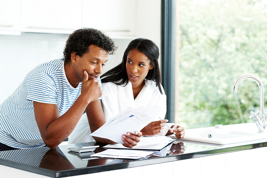 A worried young couple reading financial documents in kitchen
