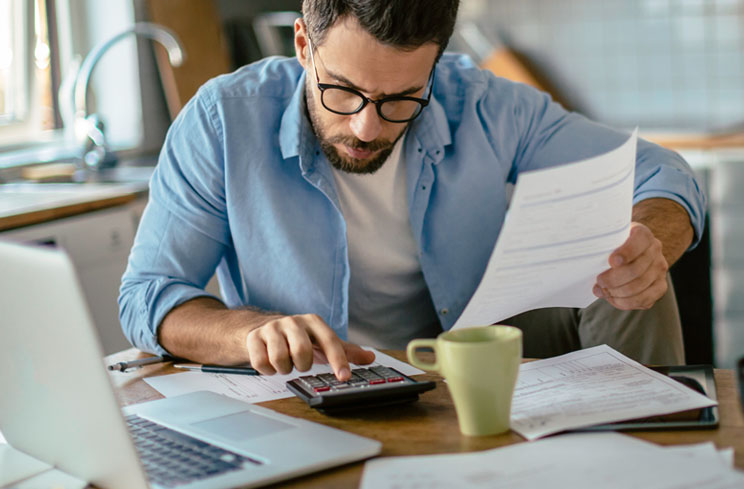 Man uses calculator while looking through financial statements