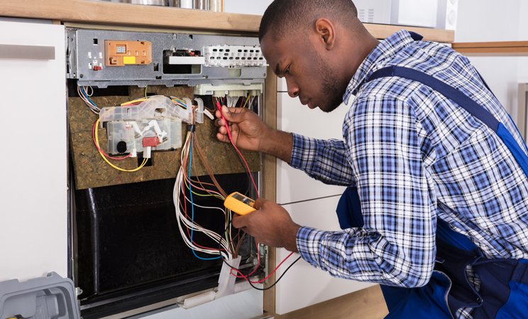 Man looks at electric meter while attempting to fix a piece of machinery