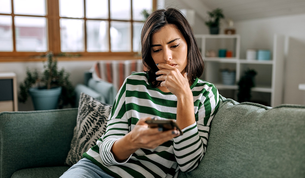 Worried Woman Looking at Phone Due to Crowdfunding Scam